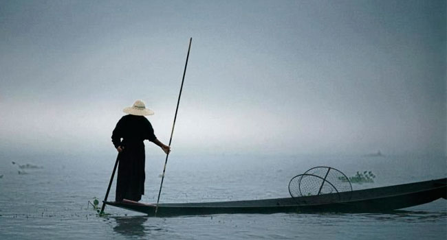 Imagem de um monge em uma canoa no meio de um lago, representado crenças e valores